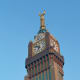 Historic clock tower with golden horns on top, Islamic architecture and ornate clock face against clear blue sky in Saudi Ara